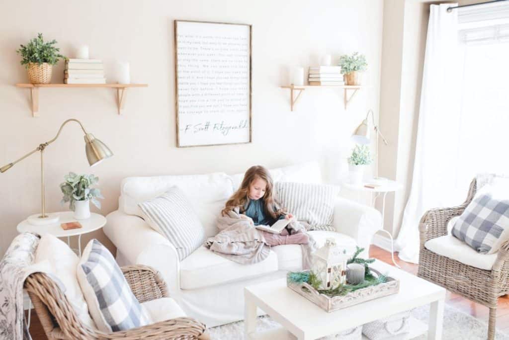 Ein helles Wohnzimmer mit natürlichen Akzenten und ein kleines Mädchen auf dem Sofa die ein Buch liest