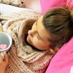 Eine Frau mit Tasse in der Hand am liegen im Feng Shui Schlafzimmer