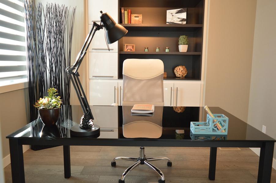 Ein Büro mit einem Schreibtisch, Stuhl, Tischlampe und einem Regal